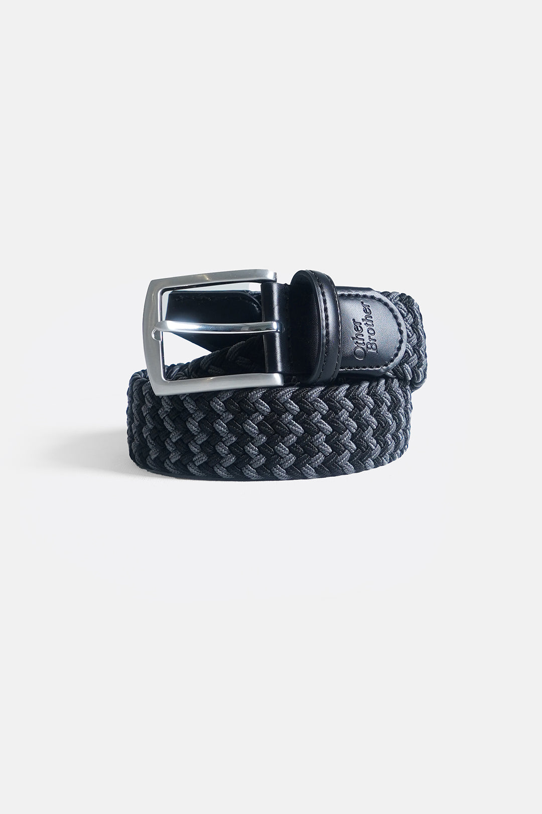 Image of A woven dark gray and black leather belt with a polished silver-tone metal buckle, coiled on a light gray background.
