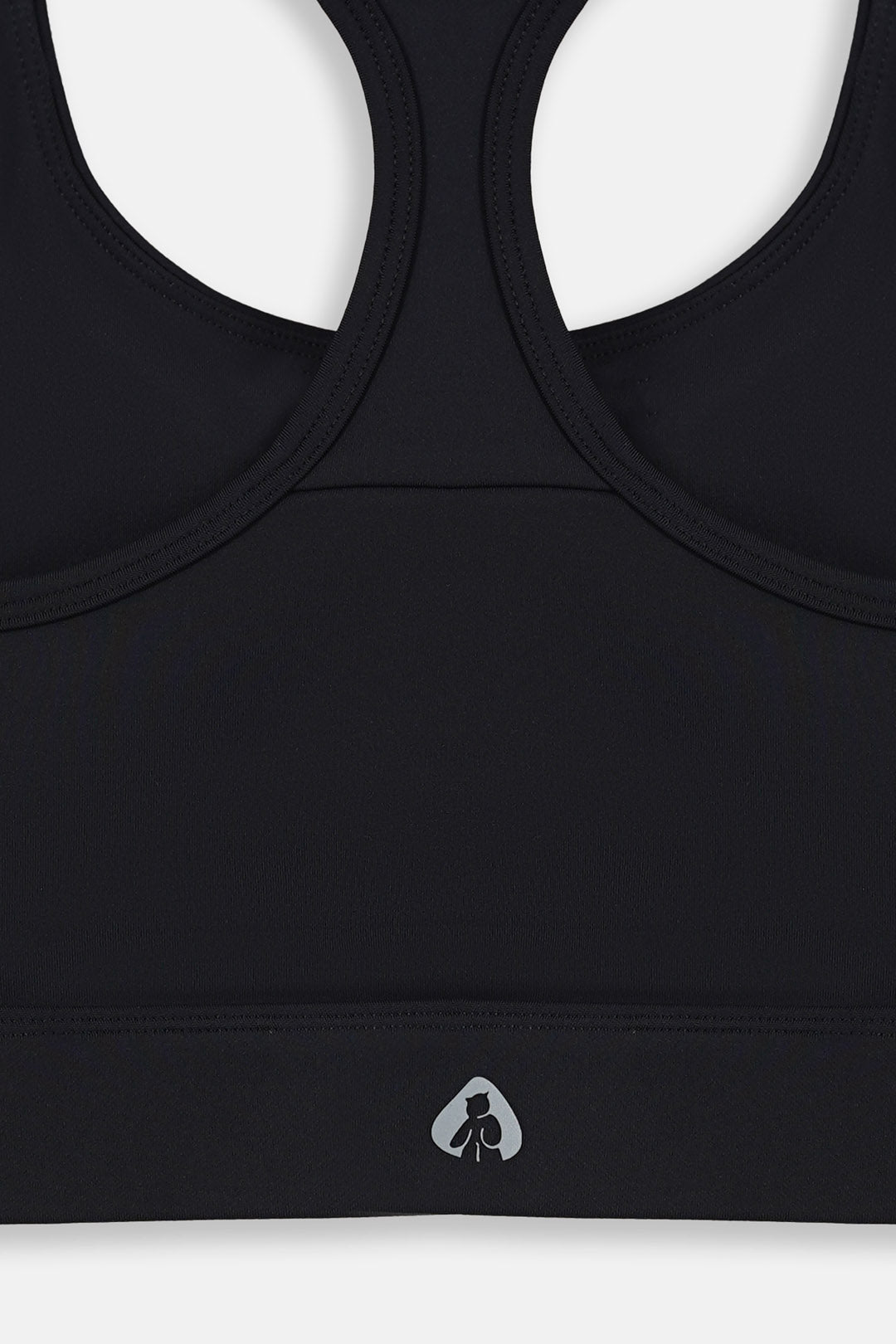 Image of Close-up of a black sports bra showing the racerback straps and a small white logo on the underband.