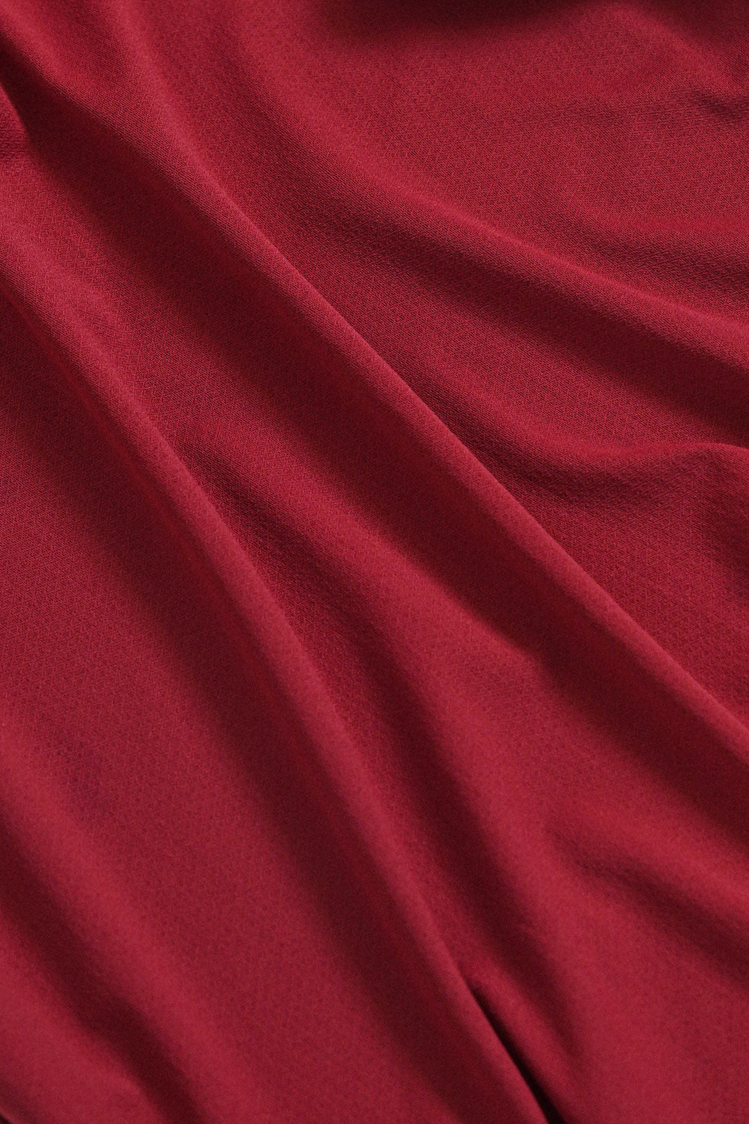 Image of A close-up of draped red fabric with soft folds and a smooth texture.