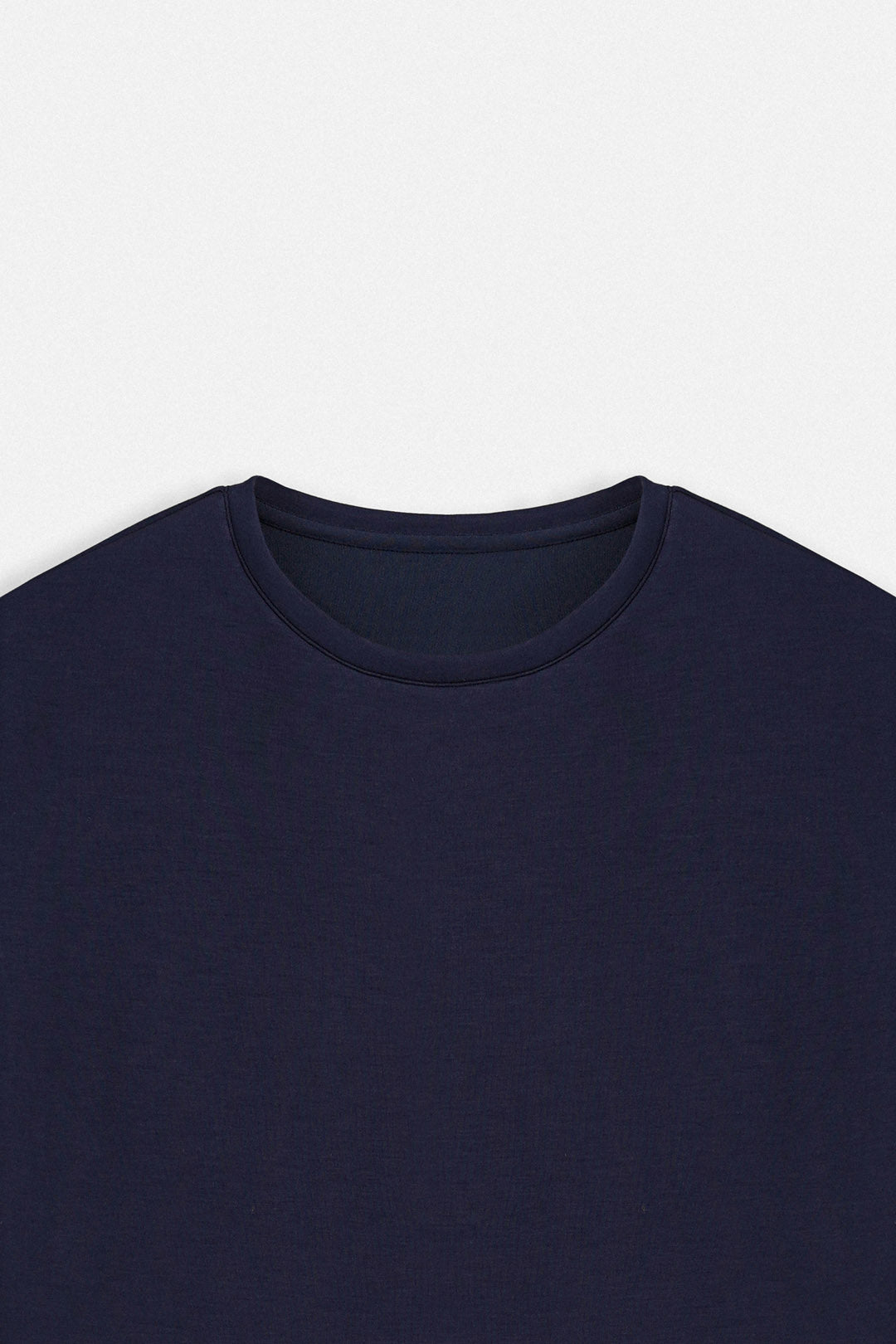 Image of Close-up of a dark navy blue crew-neck t-shirt on a light gray background.