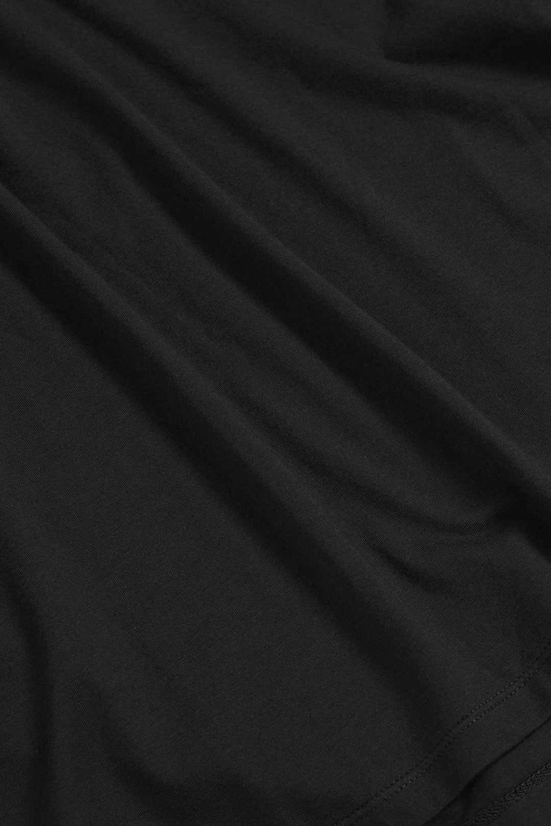 Image of A close-up of black fabric with soft folds and a hem visible at the bottom edge.