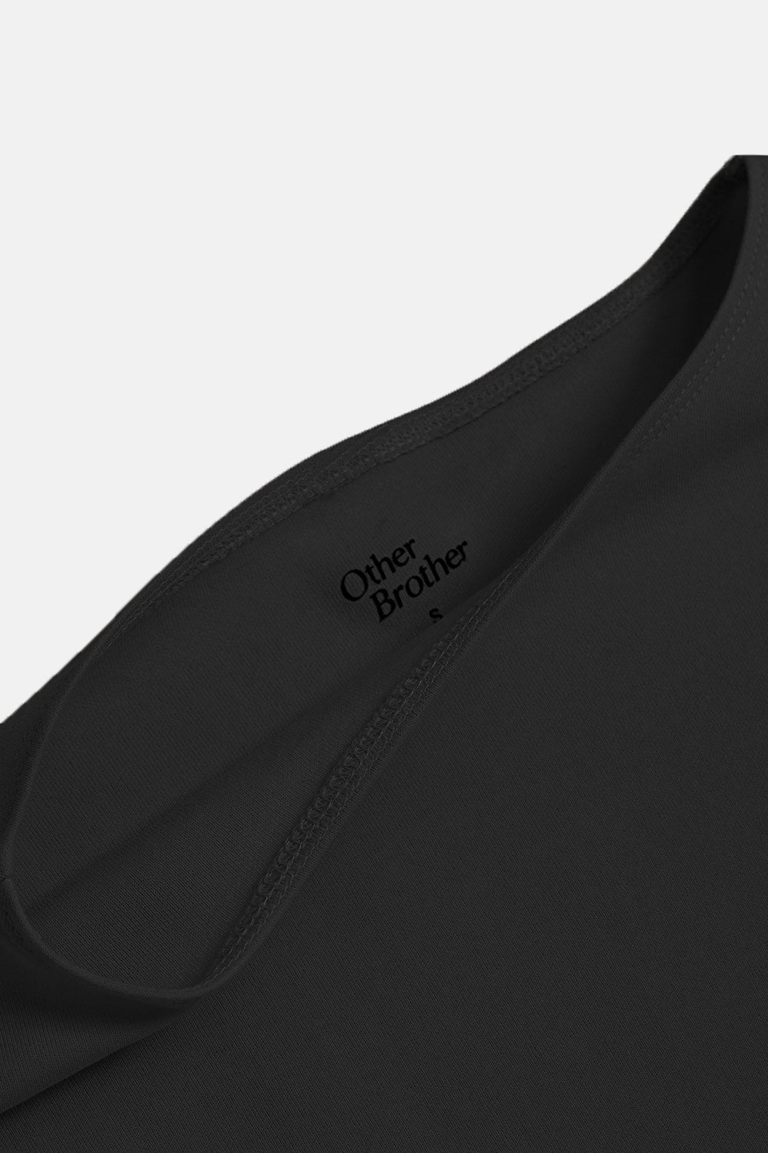 Image of Close-up of a black crewneck t-shirt showing the inner collar with the brand name 'Other Brother' printed in black on the inside neck label.