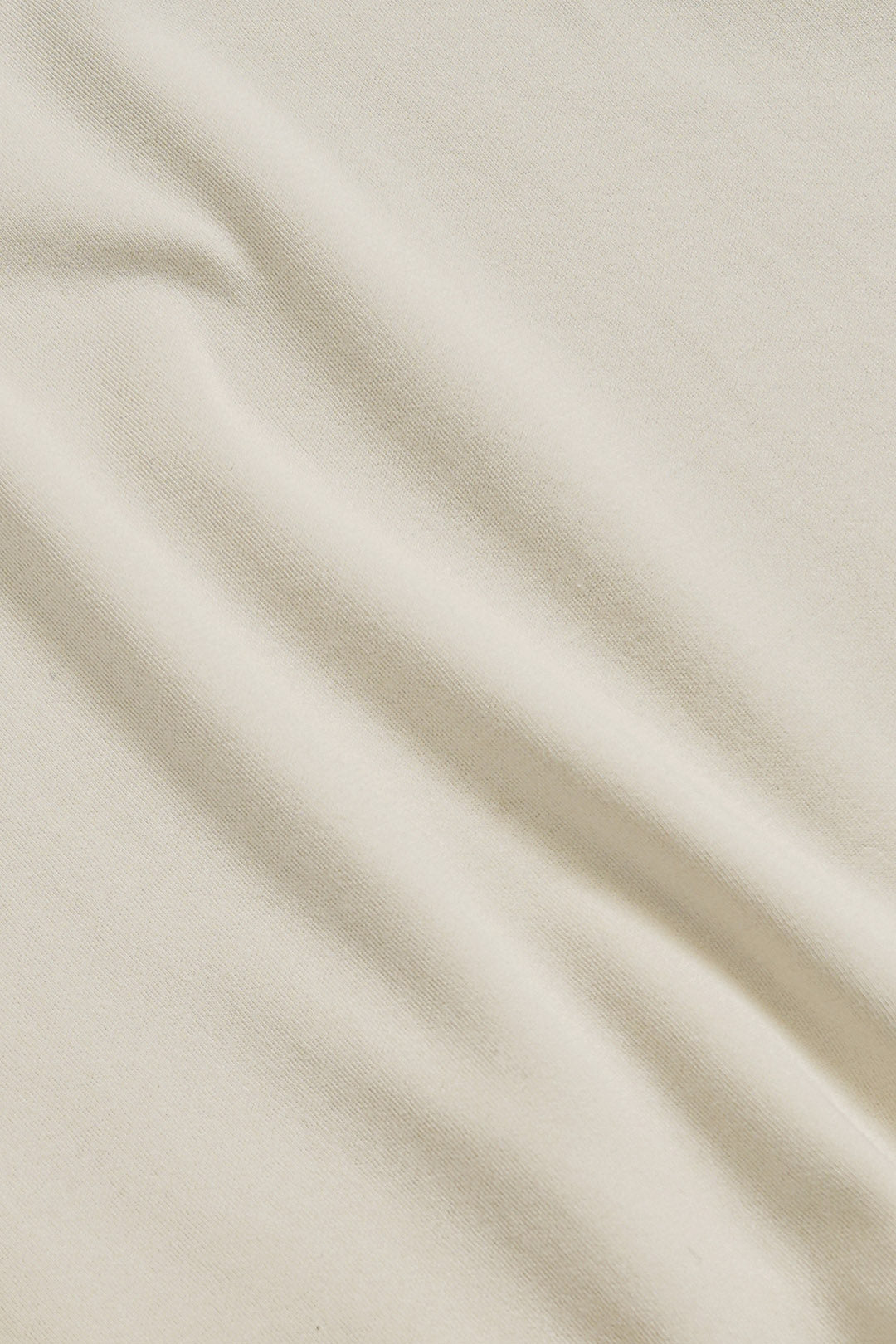 A close-up of draped off-white fabric with soft folds and a smooth texture.